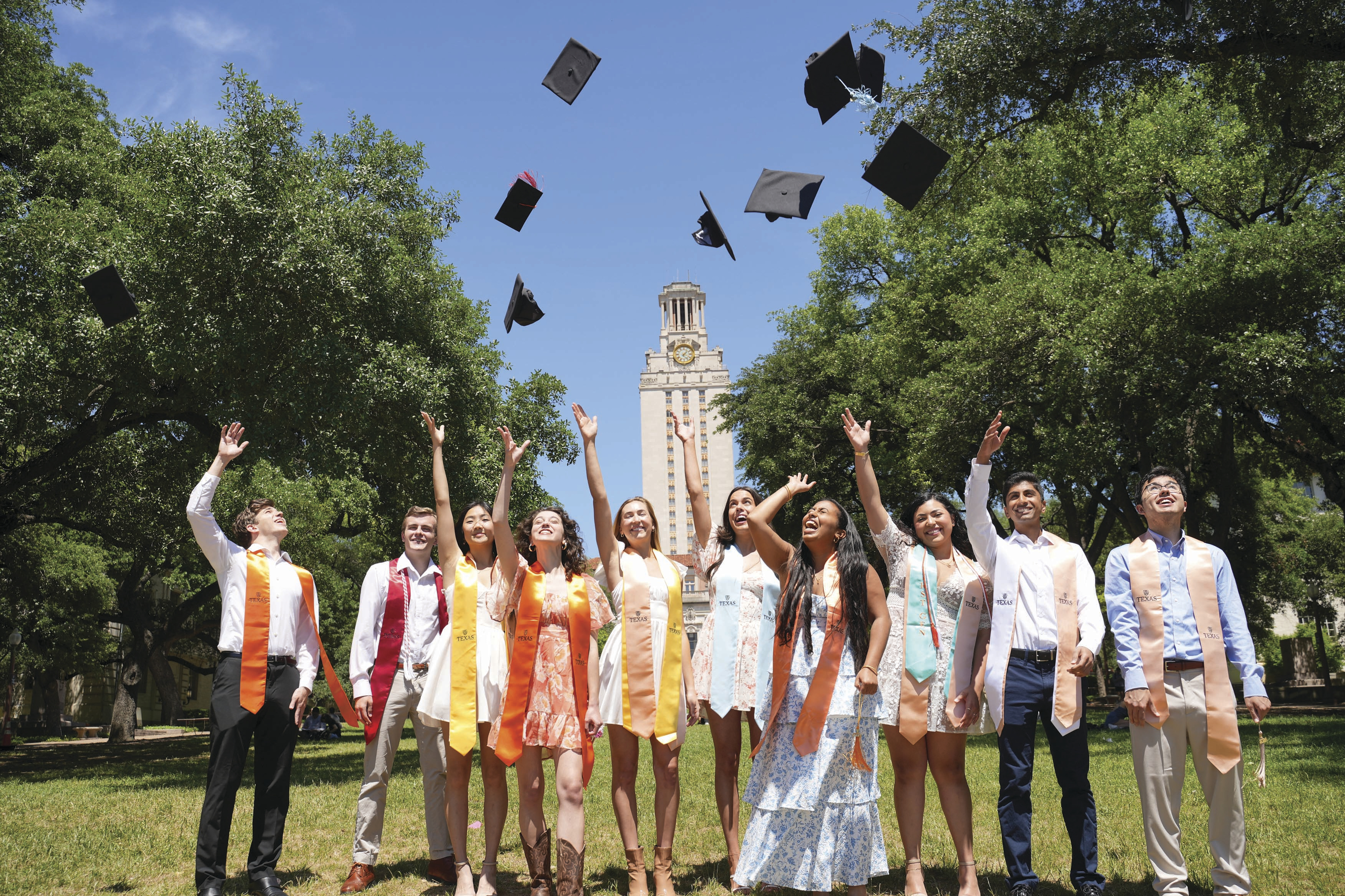 Graduates of 2024 throwing up their caps in front of the tower