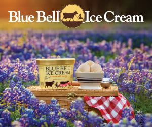 A carton of Bluebell ice cream sits in the middle of a field of bluebonnets.