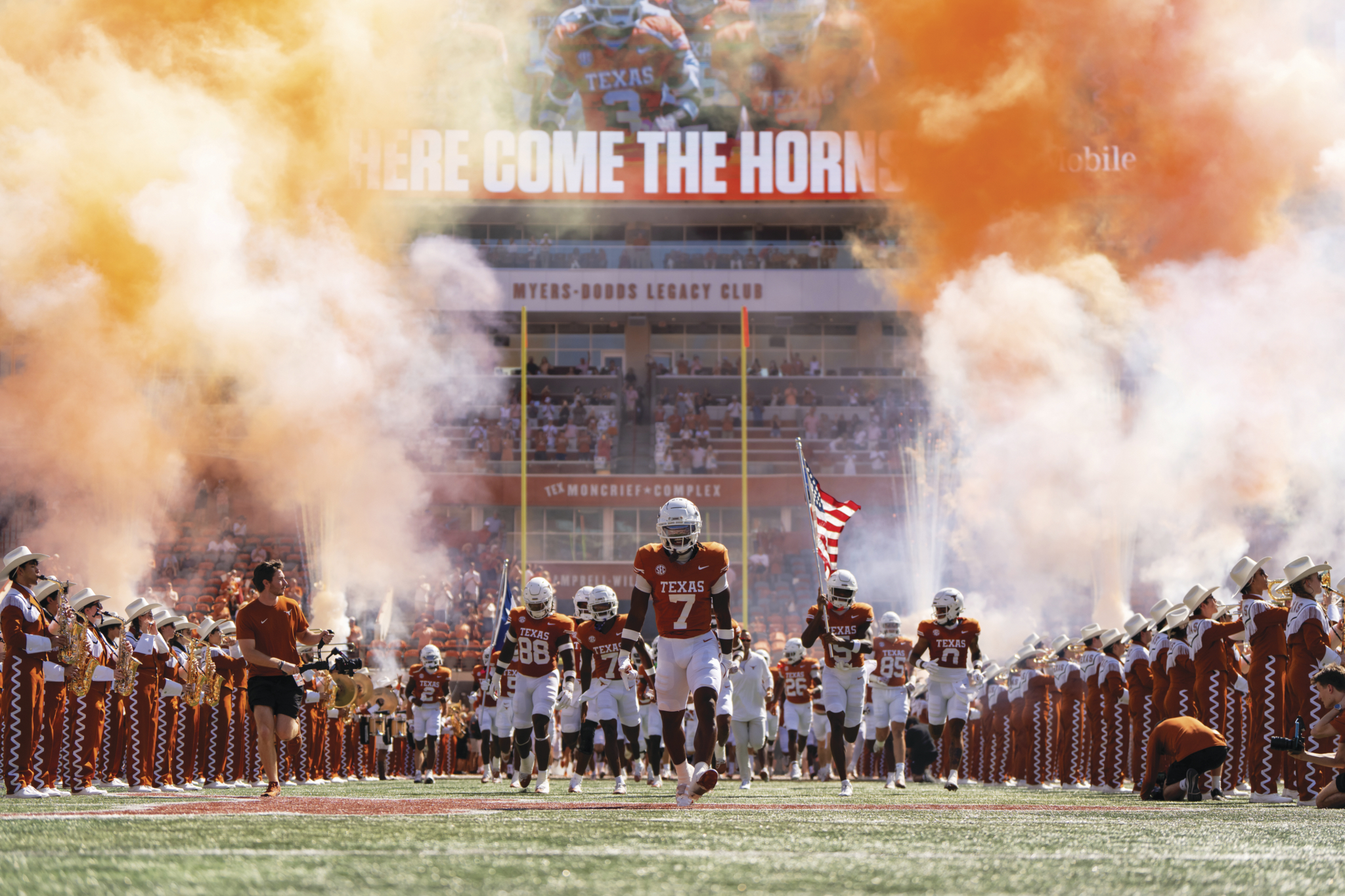 The Longhorn football team runs onto the field. 