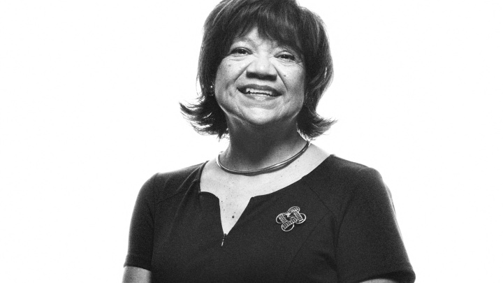 Woman on a black background wearing a black dress with a Longhorn broach.