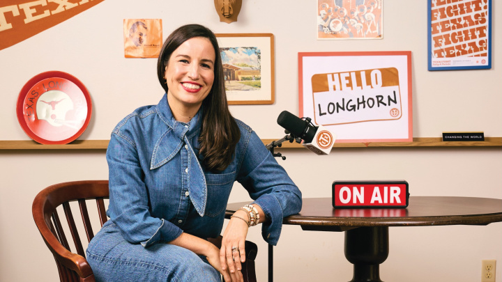 A woman in an all-denim outfit sits at a table with a red "On Air" sign.