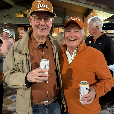 Two Longhorn fans in burnt orange at the Alumni Center at UT campus.