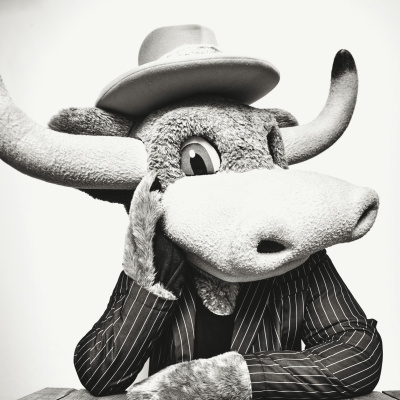 A black & white portrait of a stuffed mascot Longhorn poses in a pinstripe suit.