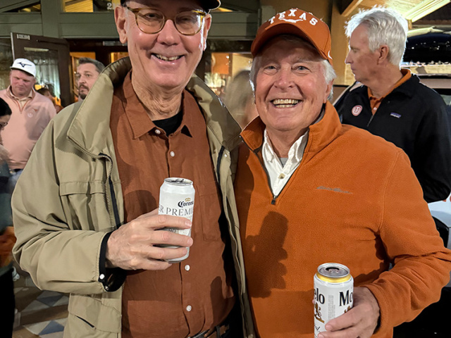 Two Longhorn fans in burnt orange at the Alumni Center at UT campus.