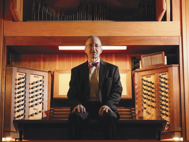 Gregory Eaton sitting in front a pipe organ