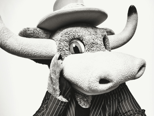 A black & white portrait of a stuffed mascot Longhorn poses in a pinstripe suit.