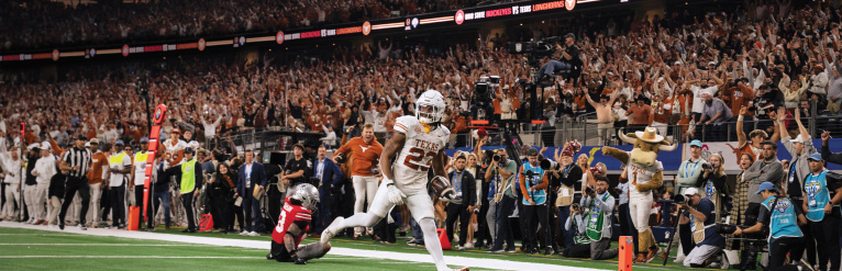A football player in white scores a touchdown.