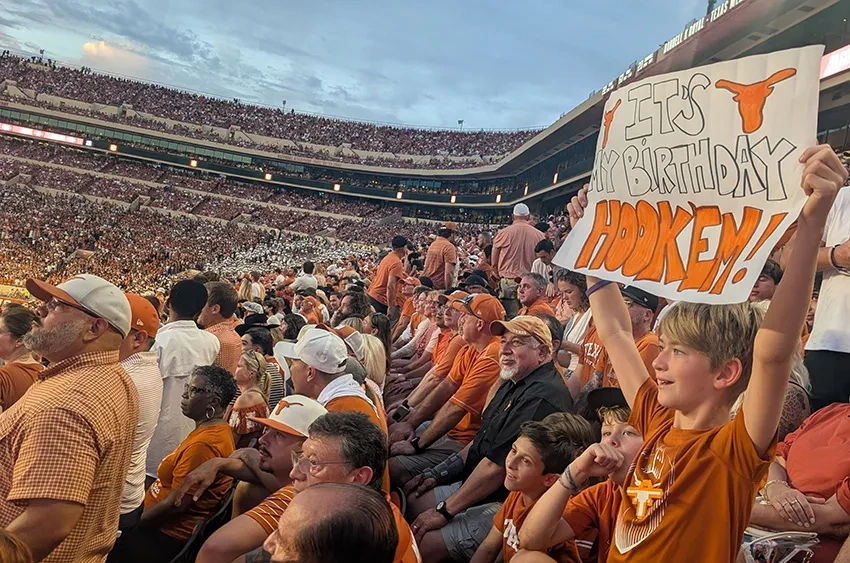 A fan holds up a sign in the crowd at a Texas home football game.