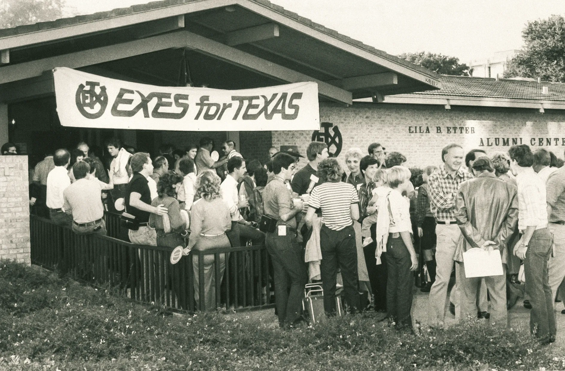 Fans crowd outside of the Alumni Center on which hangs a sign that reads EXES FOR TEXAS, 1983.