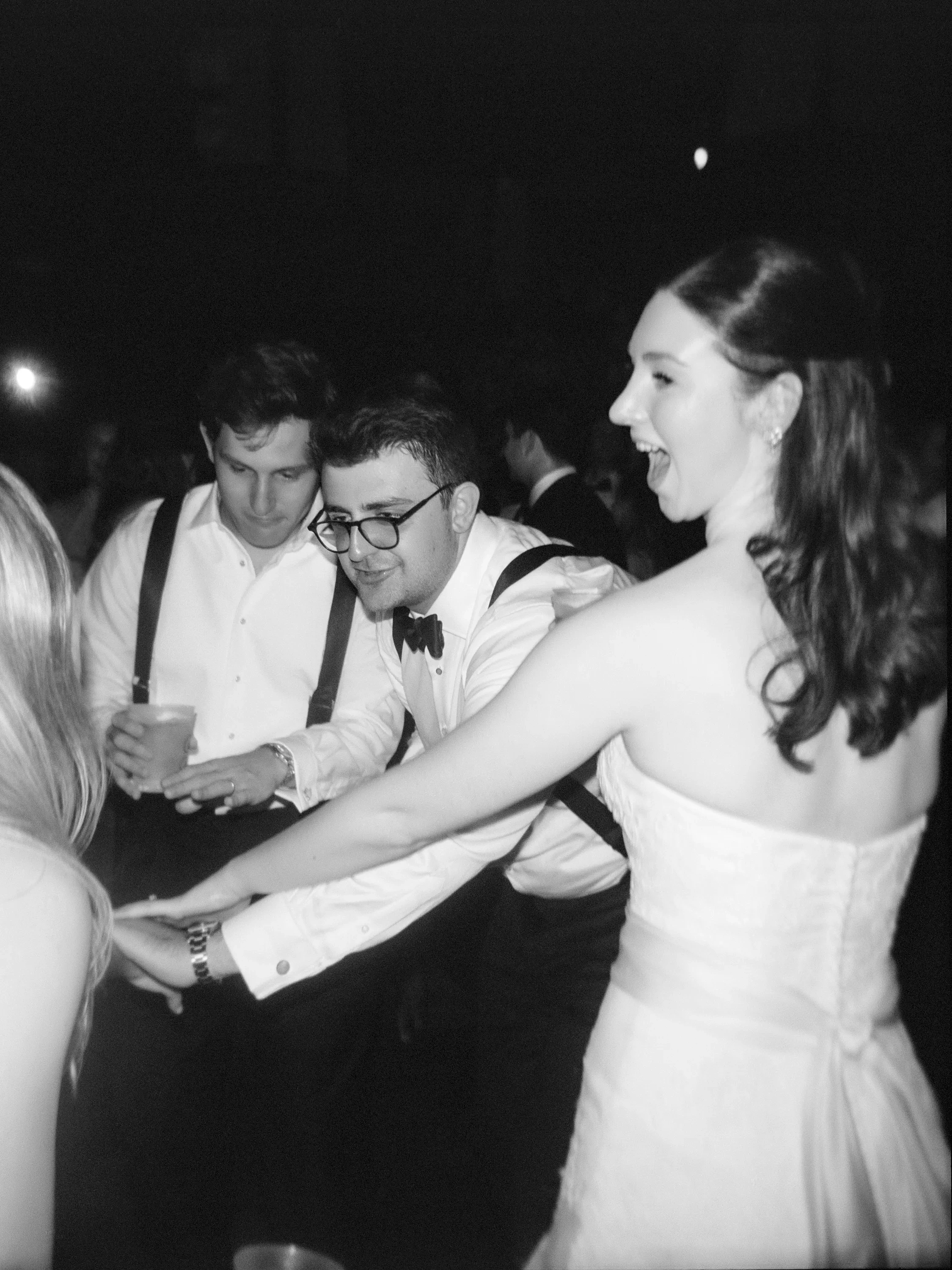 A bride, a groom, and their friend dance at a wedding.