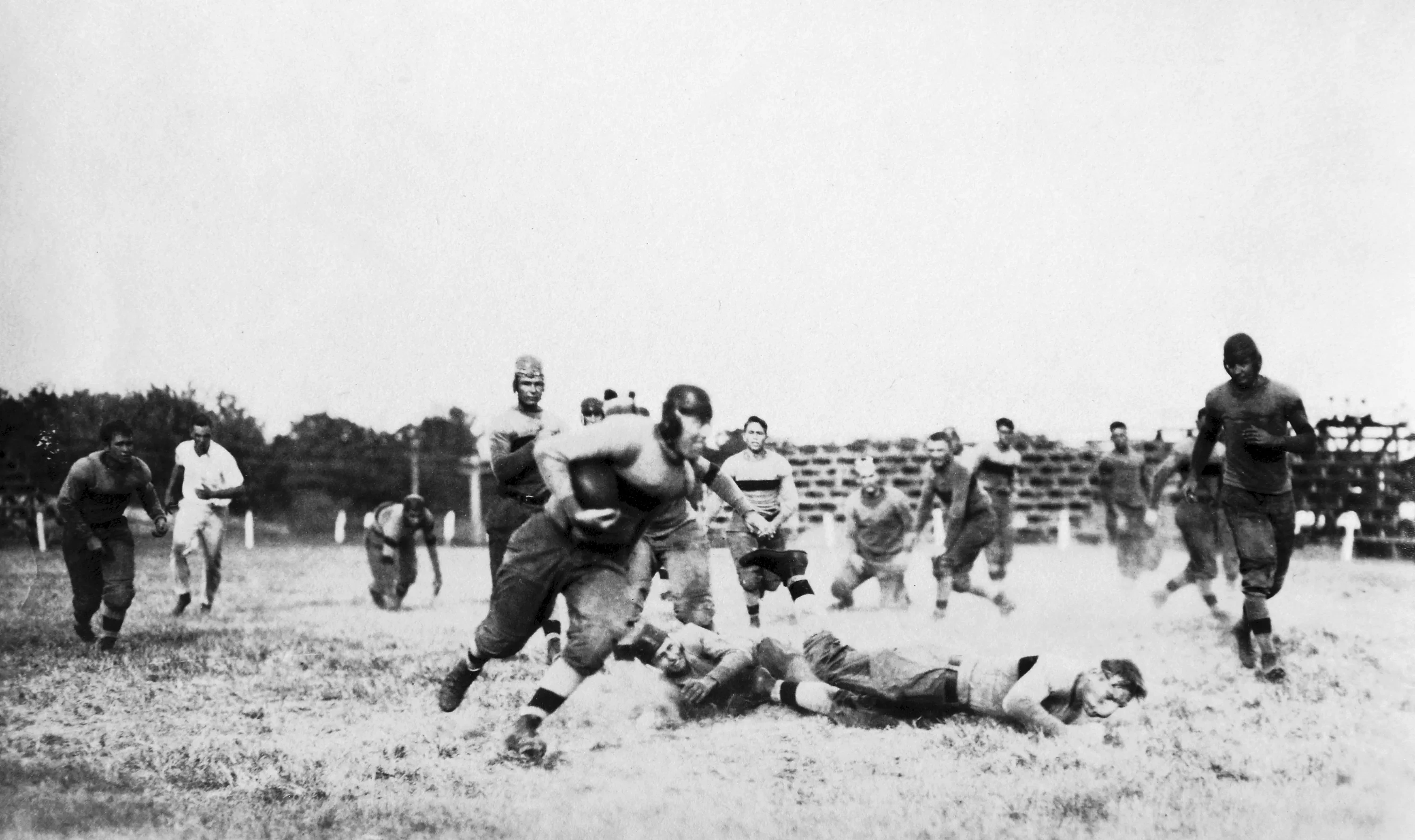An archival photo of college football players running a play, 1914.