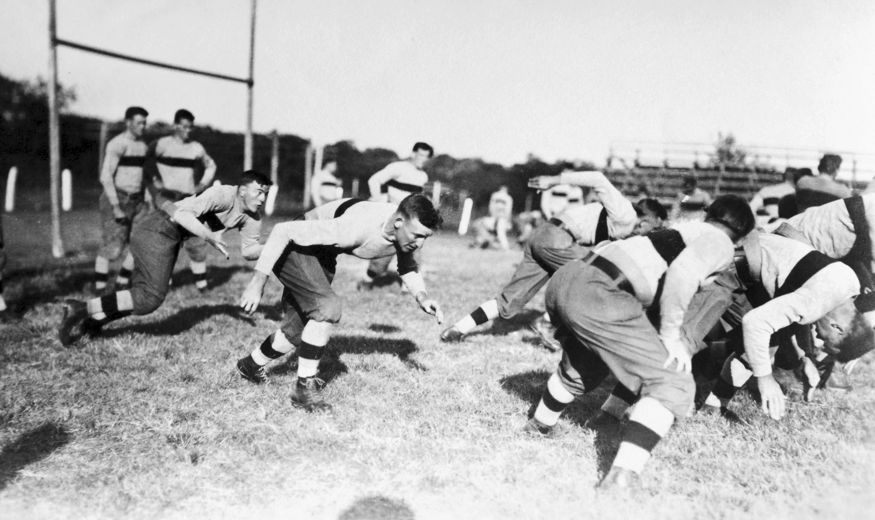 An archival photo of college football players running a play, 1914.