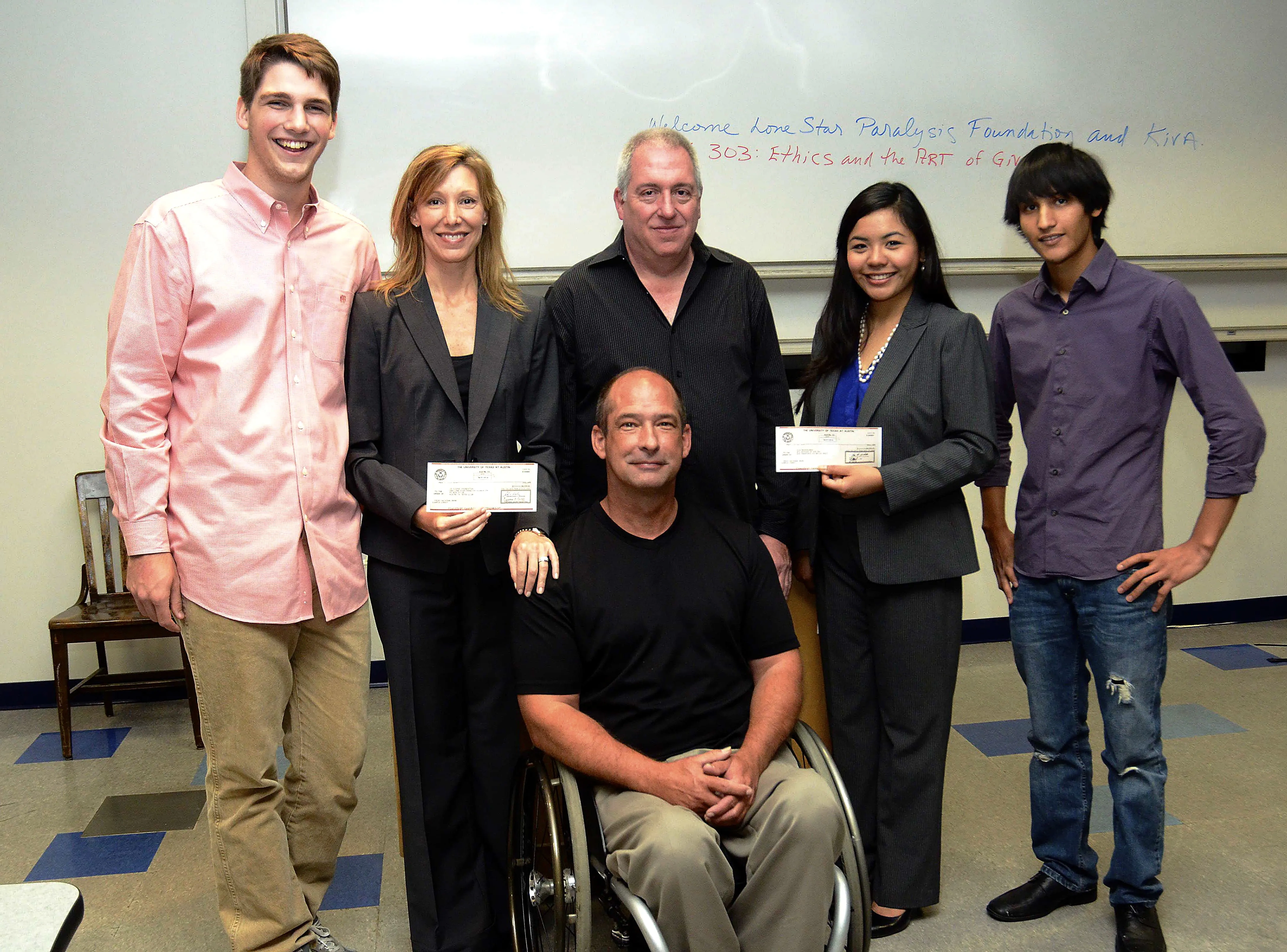 Maclean Martin (far left) and Jorge Wong (far right) present the donations to representatives from Lone Star Paralysis and KIVA. 