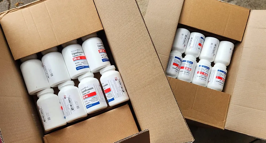 Two cardboard boxes of antibiotics in white pill jars