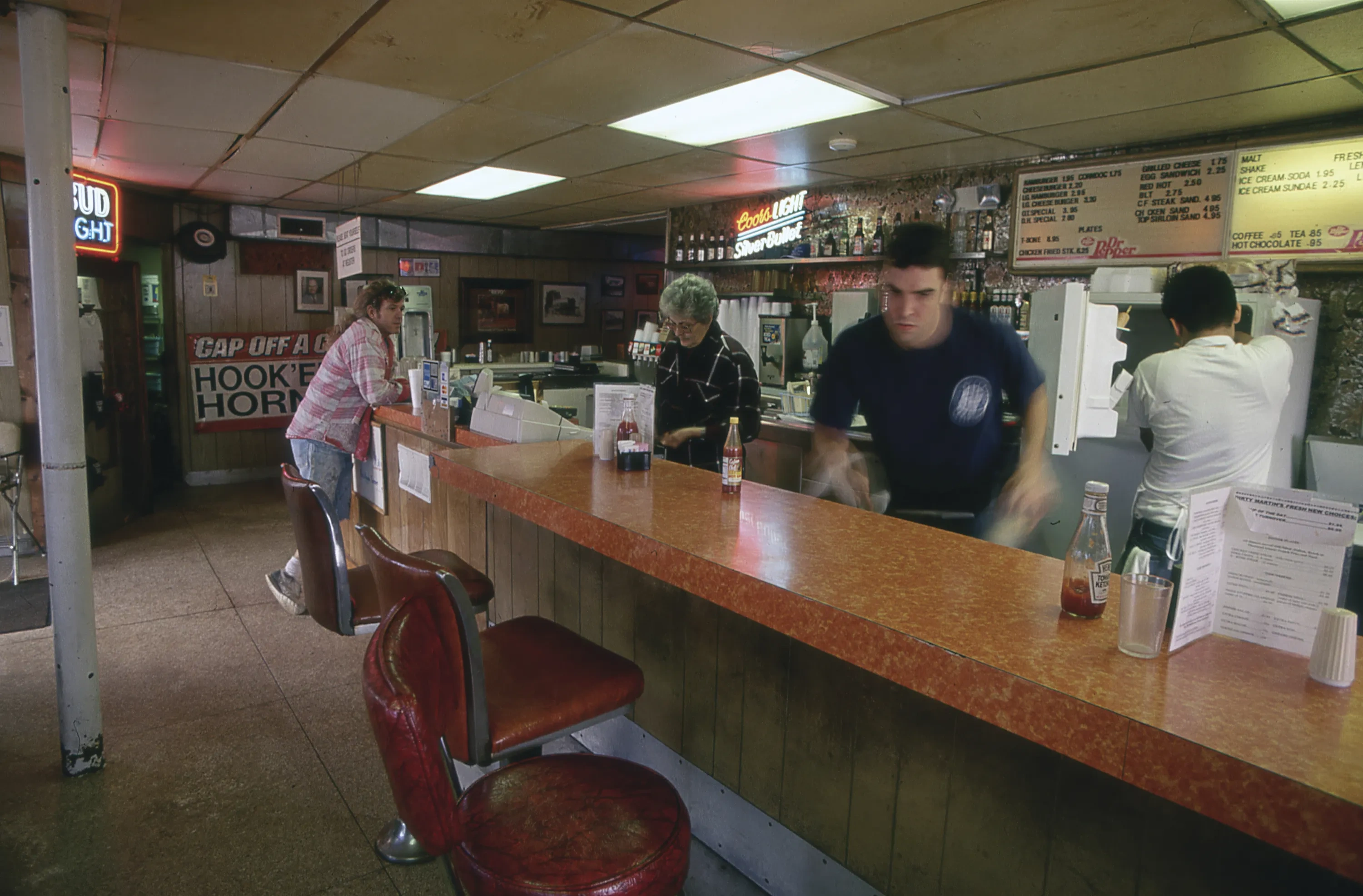 People move around and behind a diner counter.
